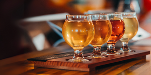 Four glasses of cider on a wooden tray with a blurred background